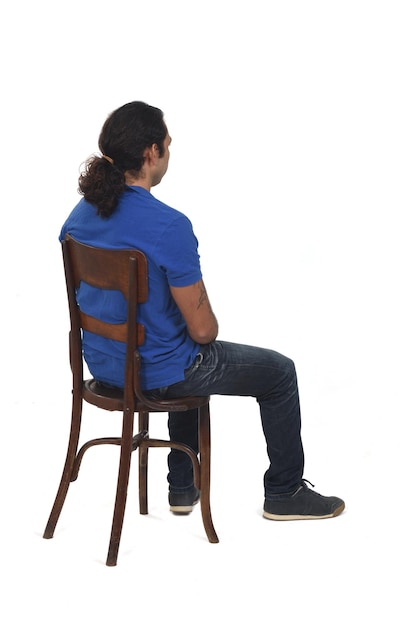 Rear view of man with ponytail and casual clothing  sitting a chair and looking  on white background