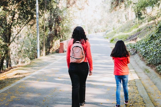 Rear view of a mother and her daughter walking up the park road