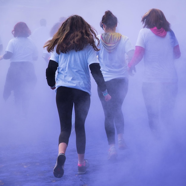 Photo rear view of people running amidst smoke