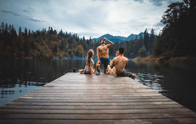 Photo rear view of people sitting by lake against sky