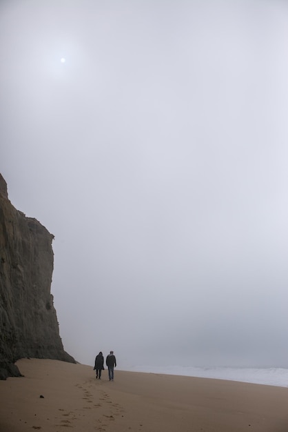 Photo rear view of people walking at beach against sky during winter