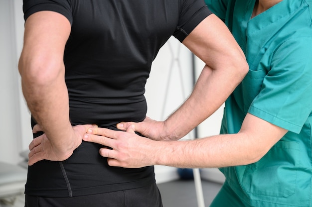 Rear view of a physiotherapist examining man back.