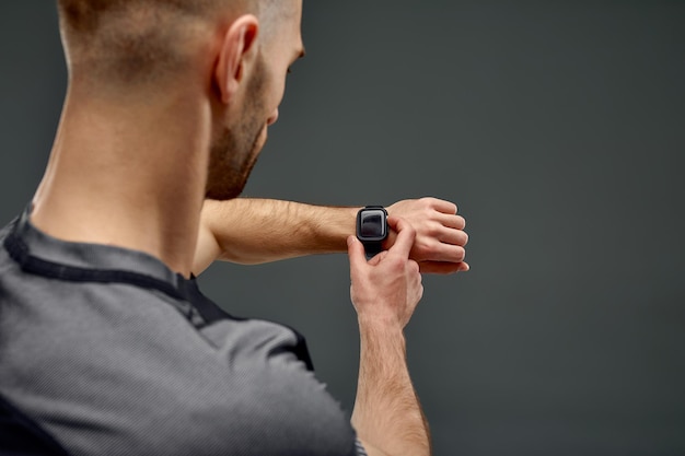 Rear view of runner checking heart rate on fitness tracker when training