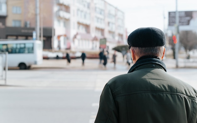 Rear view of senior man in cap and jacket standing on street grandfather walking outdoors during day Closeup copy space