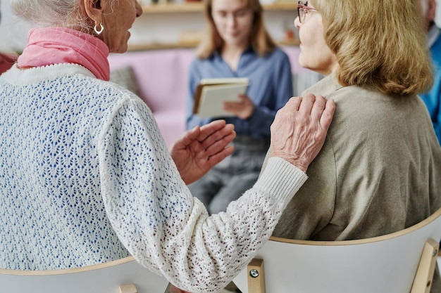 Rear view of senior woman practicing the way of communication with her friend at psychotherapy