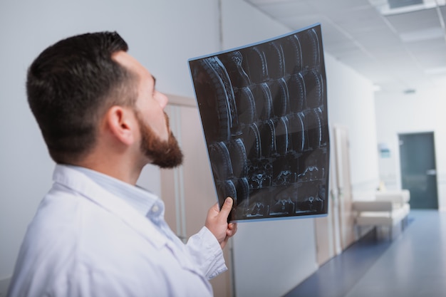 Rear view shot of a male doctor concentrating, examining MRI scan of the patient