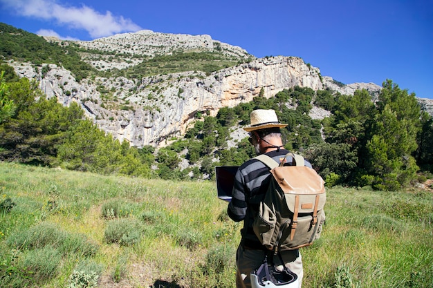 Rear view of Traveler using laptop while enjoying natural scenery outdoors