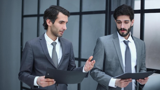 Rear view of two businessmen as they stare out a large window with a city view