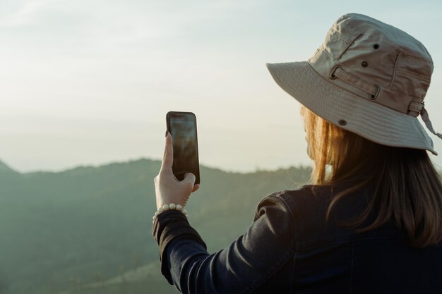 Rear view of woman photographing on mobile phone