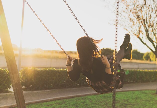 Photo rear view of woman playing on swing