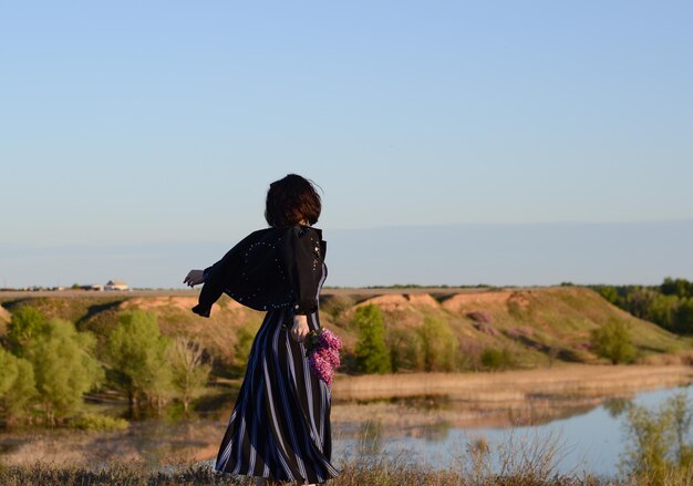 Rear view of woman standing on field against clear sky