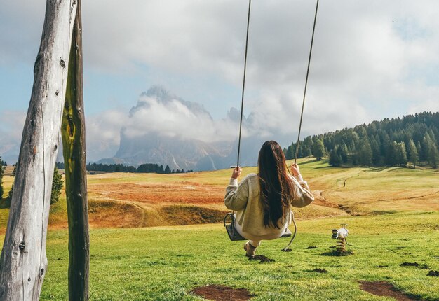 Photo rear view of woman on swing against mountains