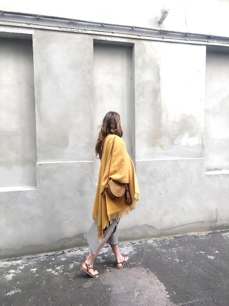 Rear view of woman walking against wall