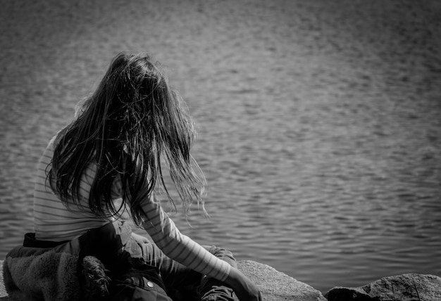 Photo rear view of woman wearing striped t-shirt overlooking rippled water