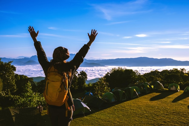 Rear view of woman with arms raised standing at campsite