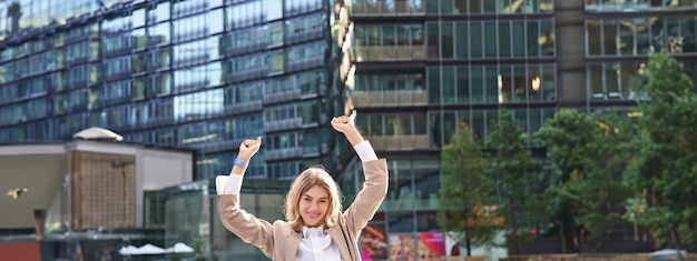 Photo rear view of woman with arms raised standing in city