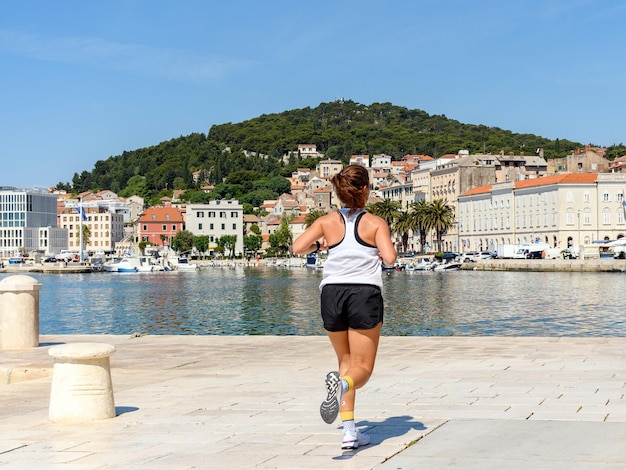 Rear view of young female jogger on a morning jog on seafront of coastal city of Split in Croatia.