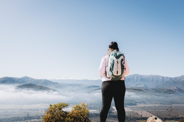 Rear view young latin woman with backpack on, at the top of a hill