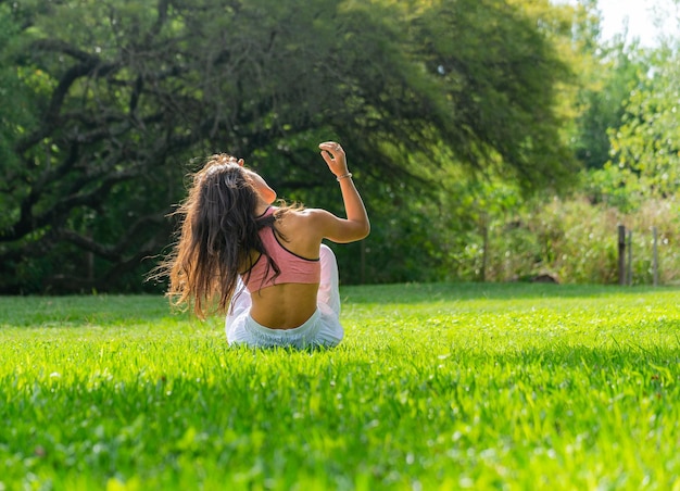 Rear View of Young Woman Sitting on a Green Meadow Enjoying the Sun LightOutside ConceptCopy Space