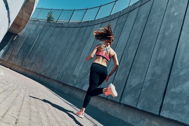 Rear view of young woman in sports clothing running outdoors