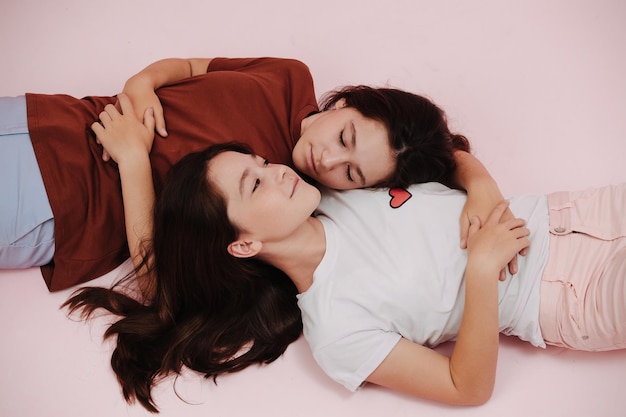 Reaxing twin girls lying on the floor in opposite resting heads on one another