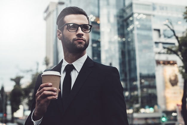 Rebooting after hard working day. Confident young man in formalwear holding coffee cup