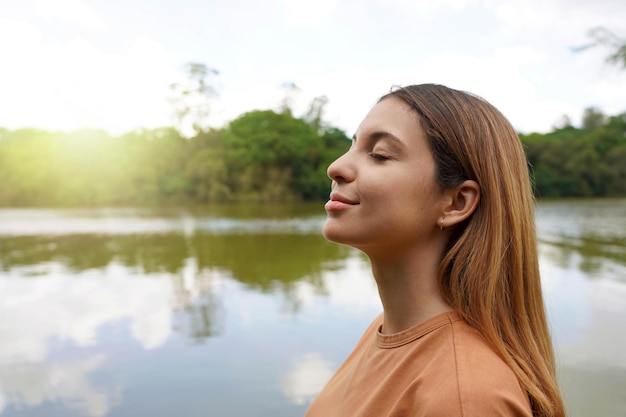 Reconnect with nature Side view of young woman with closed eyes enjoying breathing in tropical park of Brazil