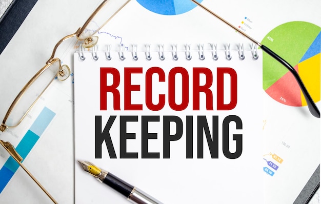 RECORD KEEPING word on notepad with glasses and chart