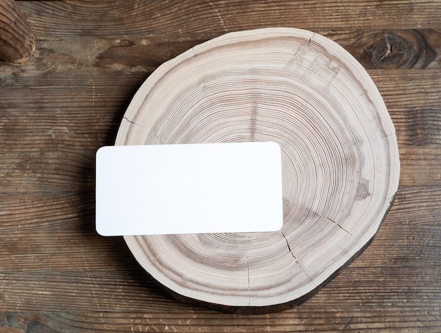 Rectangular empty paper card on wooden cross slice on old weathered rustic wooden table Mock up Copy space View from above Horizontal orientation