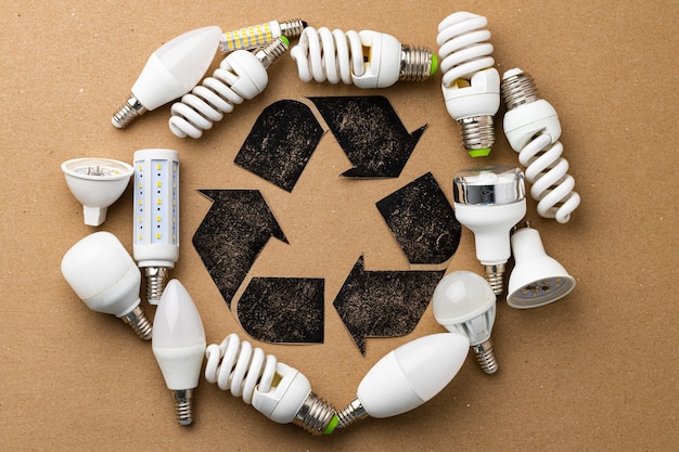 Recycling symbol surrounded by used light bulbs on craft paper