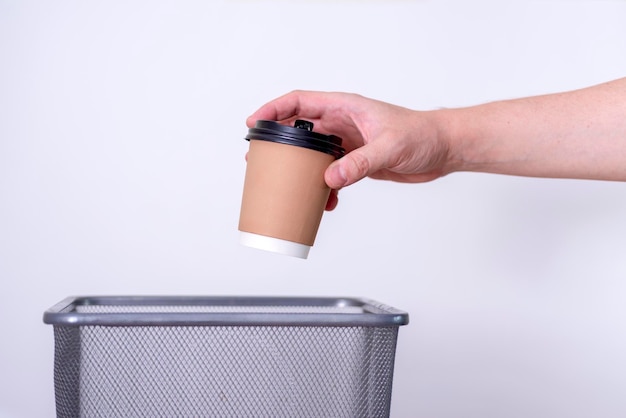 Recyclingseparate waste collection hand throws a cup of coffee into the trash can