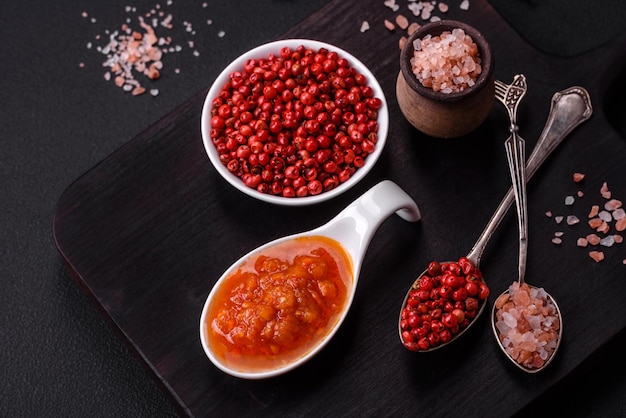 Red adjika sauce or ketchup with spices and herbs on a dark concrete background