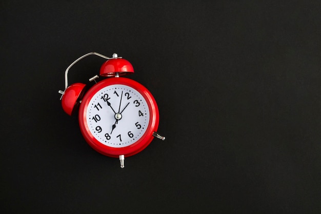 Red alarm clock on the black background Copy space Top view