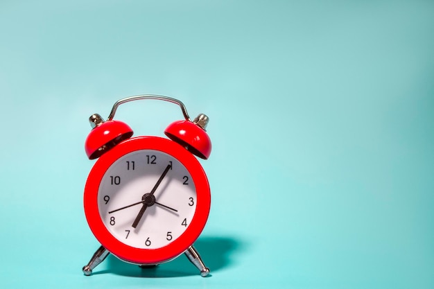 Red alarm clock on blue background with copy space