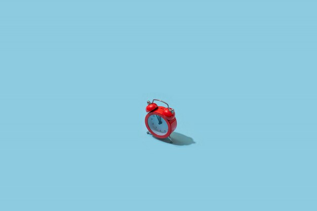 Red alarm clock on pastel blue background. Creative idea. minimal concept. Isometric, harsh light