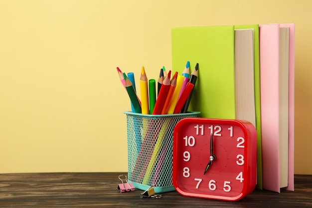 Red alarm clock and school accessories on a beige background Back to school concept