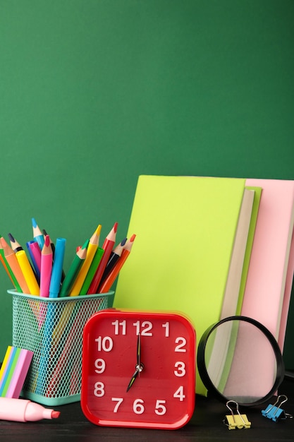 Red alarm clock and school accessories on a green background Back to school concept