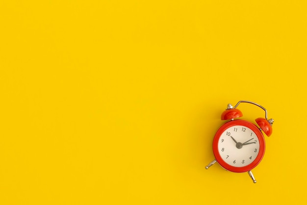 Red alarm clock with space for text on yellow background