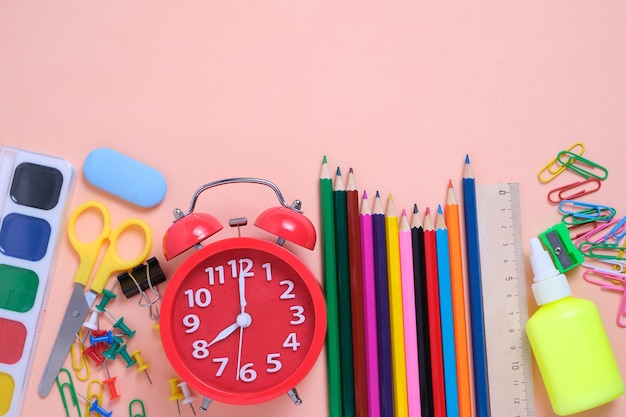 Red alarm clockschool supplies and stationery on a pink background