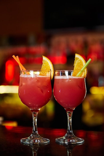 Red Alcoholic cocktails decorated with half slices of orange on the bar counter of a nightclub