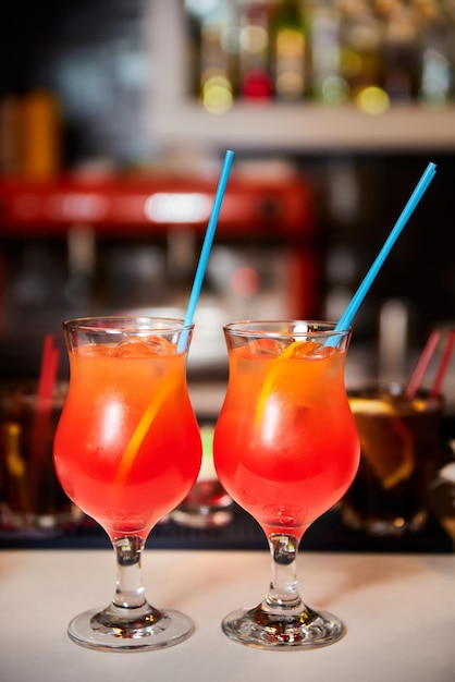 Red Alcoholic cocktails decorated with slices of orange on the bar counter