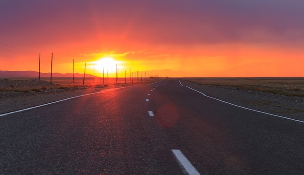 Red amazing sunset over an infinitely long asphalt road in the Altai Republic