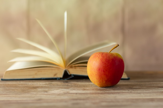 Red apple on blurred a book retro wall background,