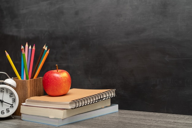 Red apple, books and pencils holder on the desk