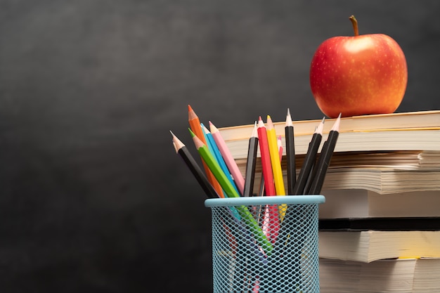 Red apple, books and pencils holder on the desk