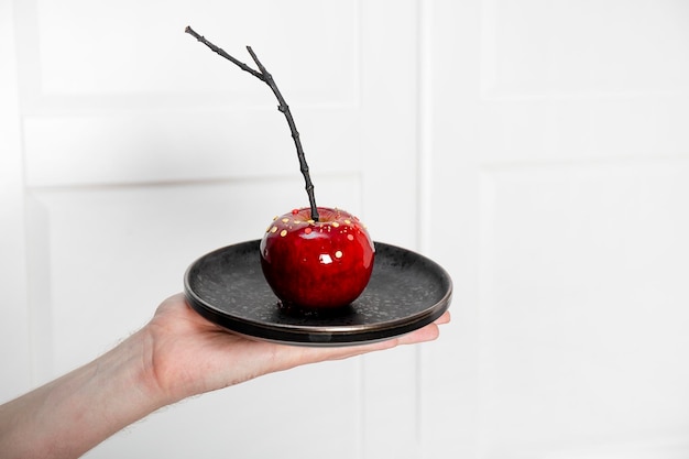 Red apple in caramel with sugar decor on a plate an original treat for a festive Halloween table