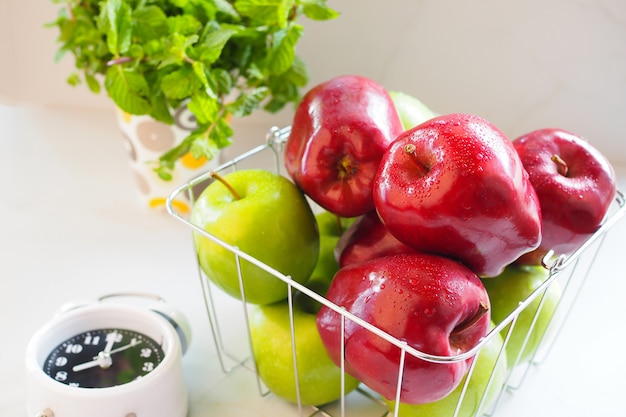 Red apple and green apple in basket on white table