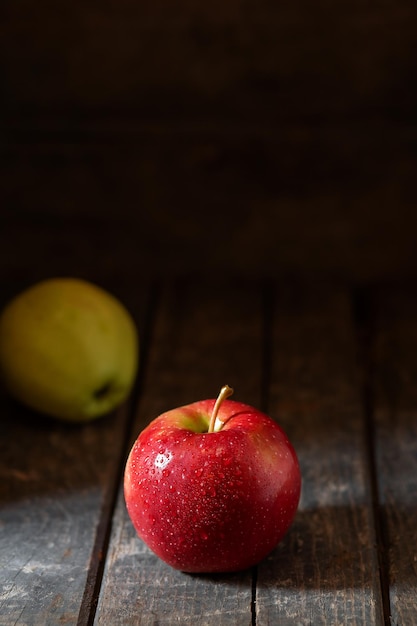 Red apple in water drops on wooden background texture