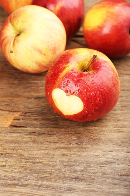 Red apple with heart on wooden table, close-up