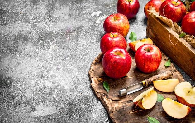 Red apples on a chopping Board with box. On rustic table.